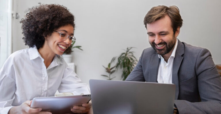 Dois profissionais analisando dados financeiros com expressão positiva, representando consultoria contábil estratégica.
