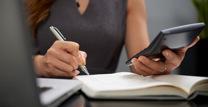 Pessoa analisando fluxo de caixa com gráficos e calculadora sobre a mesa